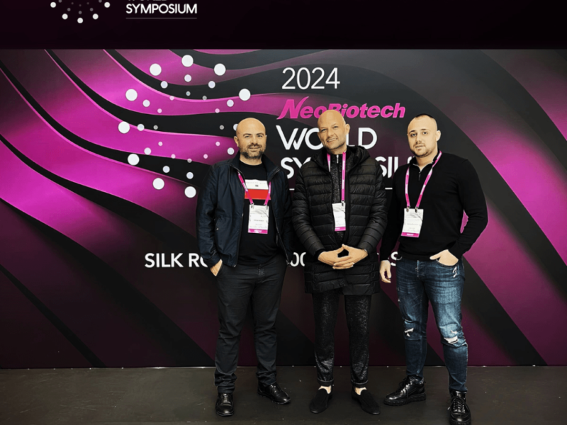 Трима участници на симпозиум Neobiotech 2024 с лого на събитието на фона.