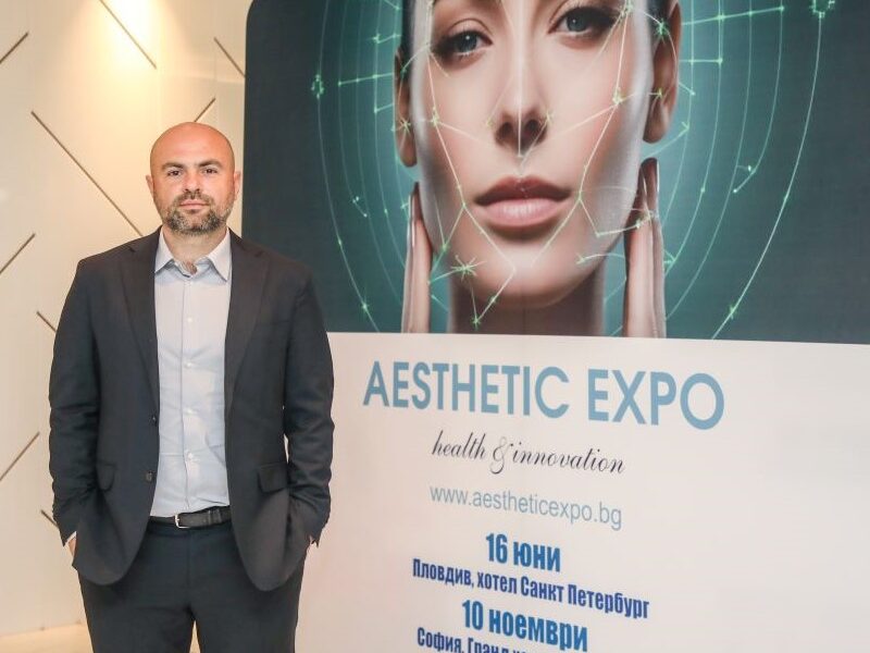 Мъж стои пред реклама на Aesthetic Expo с дата и информация за събитието.