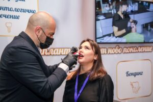 Стоматолог извършва процедура на пациент с маска в стоматологичен кабинет.